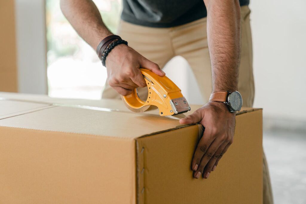 A person using tape to secure a cardboard box